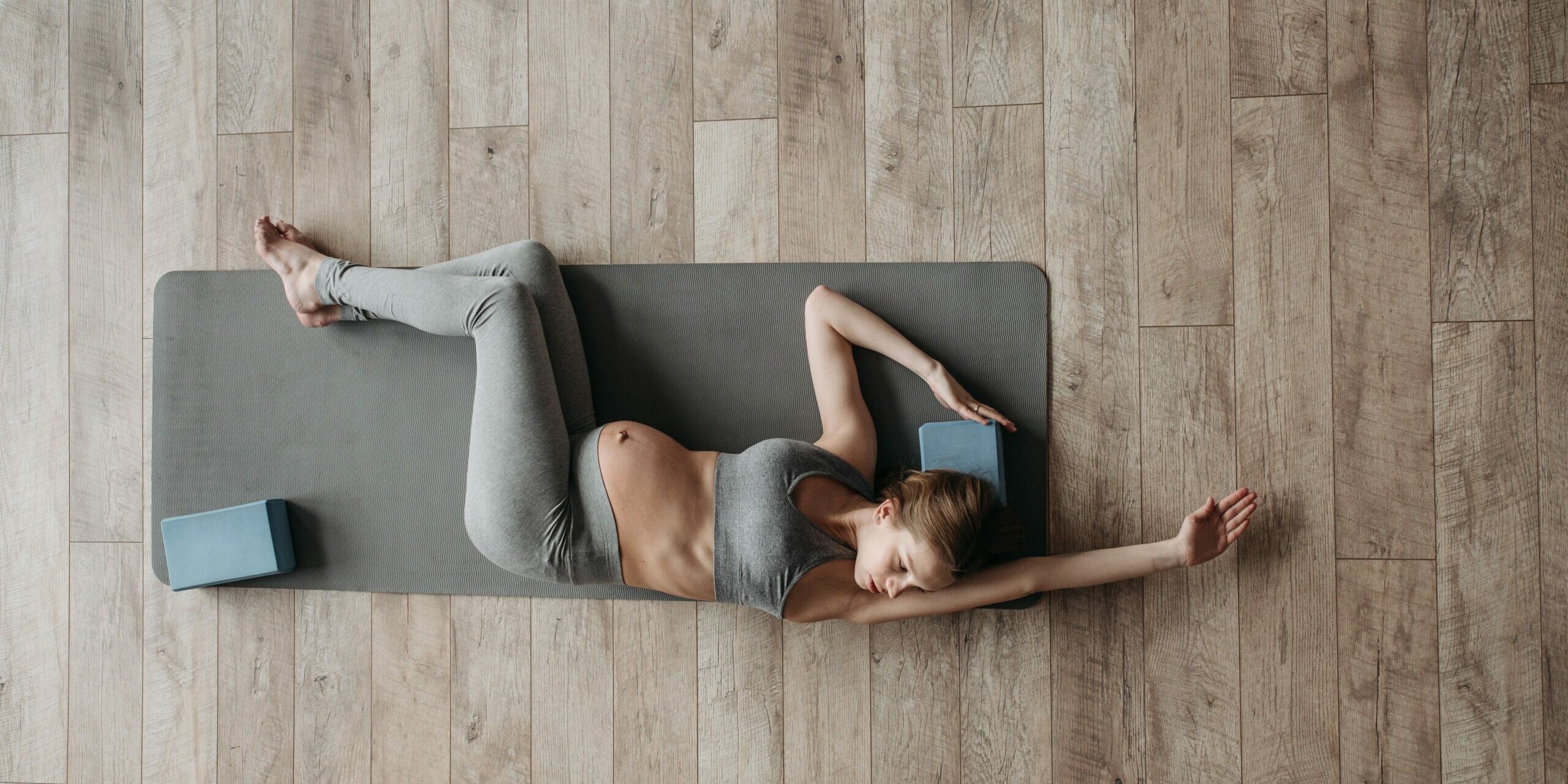 femme enceinte qui réalise un exercice de mobilité sur un tapis
