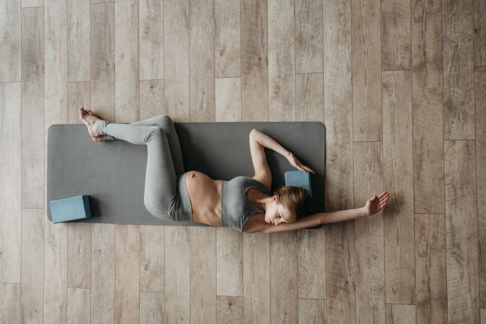 femme enceinte qui réalise un exercice de mobilité sur un tapis